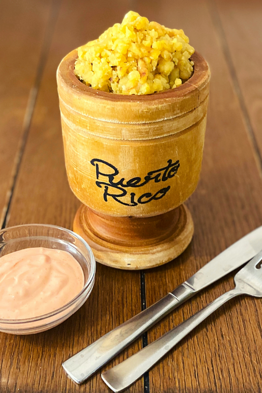 A traditional Puerto Rican dish presented in a wooden mortar and pestle (pilon)