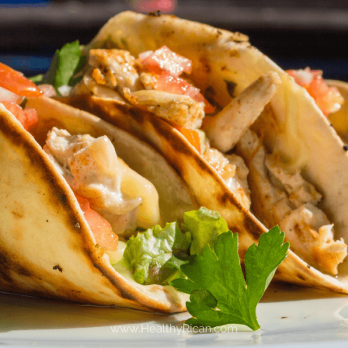 Delicious chicken and avocado tacos on a rustic wooden table, garnished with fresh cilantro and lime slices, perfect for a flavorful meal.