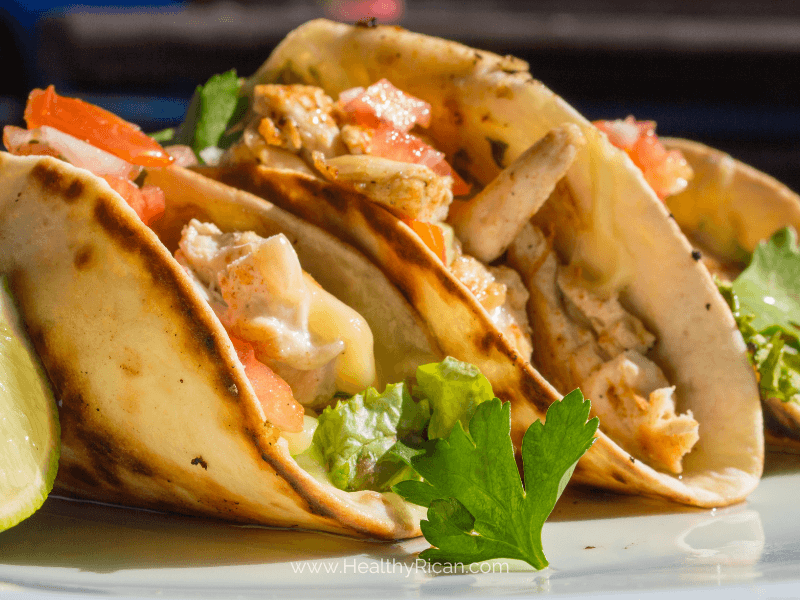 Delicious chicken and avocado tacos on a rustic wooden table, garnished with fresh cilantro and lime slices, perfect for a flavorful meal.