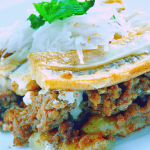 A delicious plate of Pastelón, a healthy Puerto Rican recipe featuring layers of ground beef, plantains, and a topping of fresh onions and cilantro. This Puerto Rican dish is a perfect blend of savory and sweet flavors, showcasing a healthy way to enjoy traditional Puerto Rican cuisine.